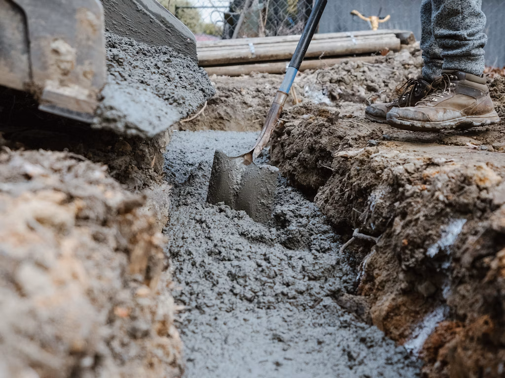 Man moving concrete with shovel.